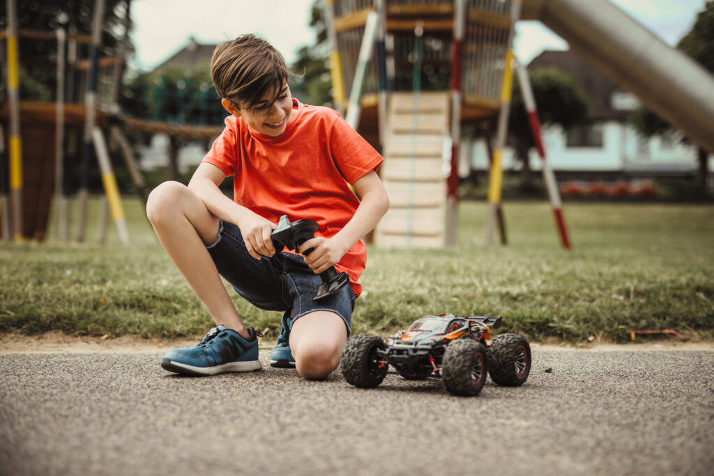 A child playing outside with a remote control car toy.