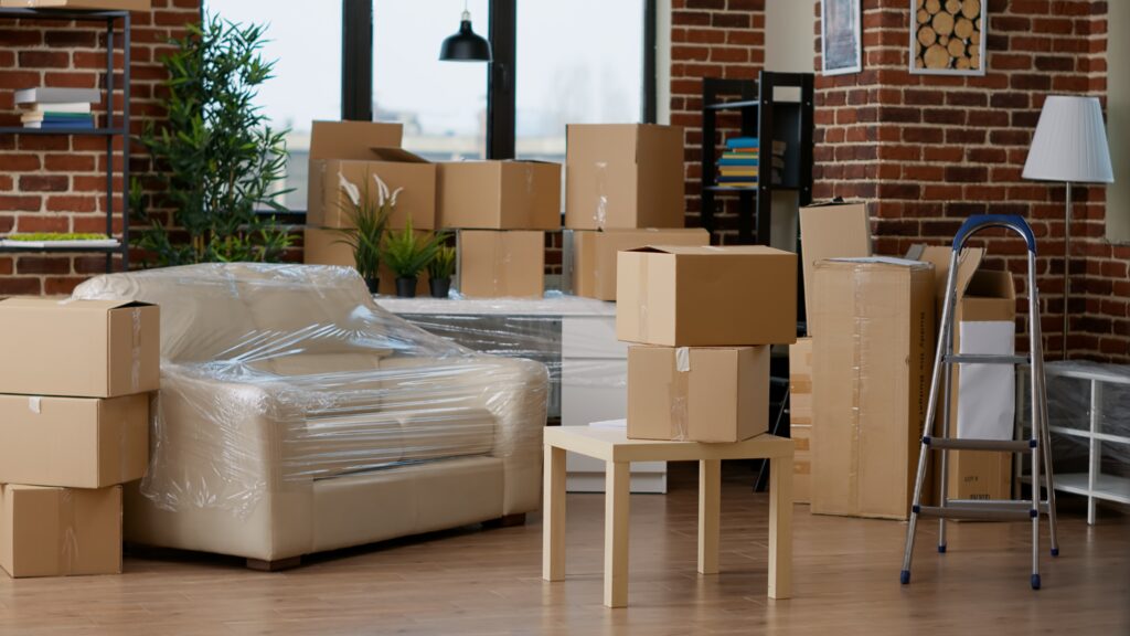 An image of a house packed up with a sofa wrapped up and various cardboard boxes ready for storage.